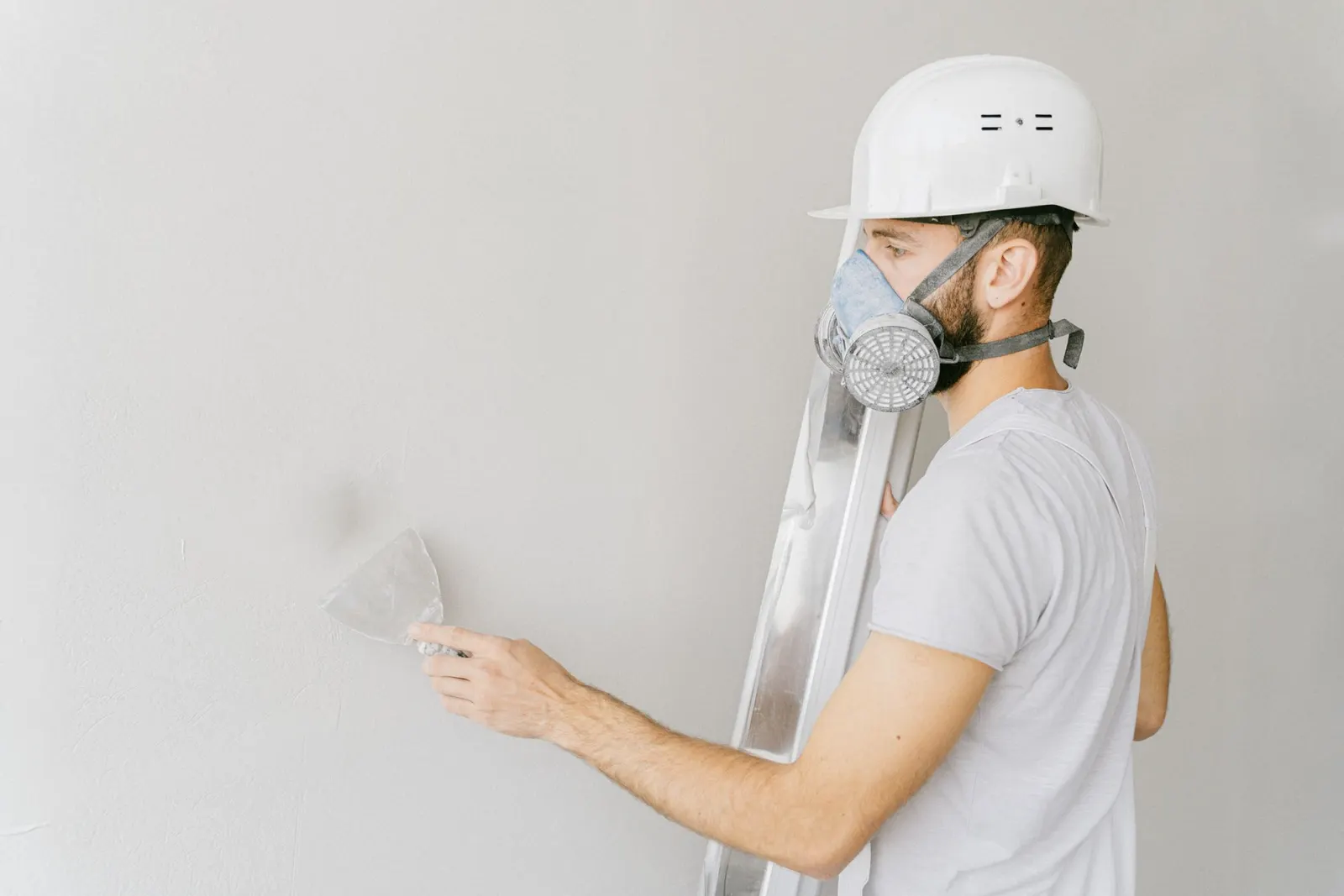 Applicator in a mask smoothing a wall with a trowel
