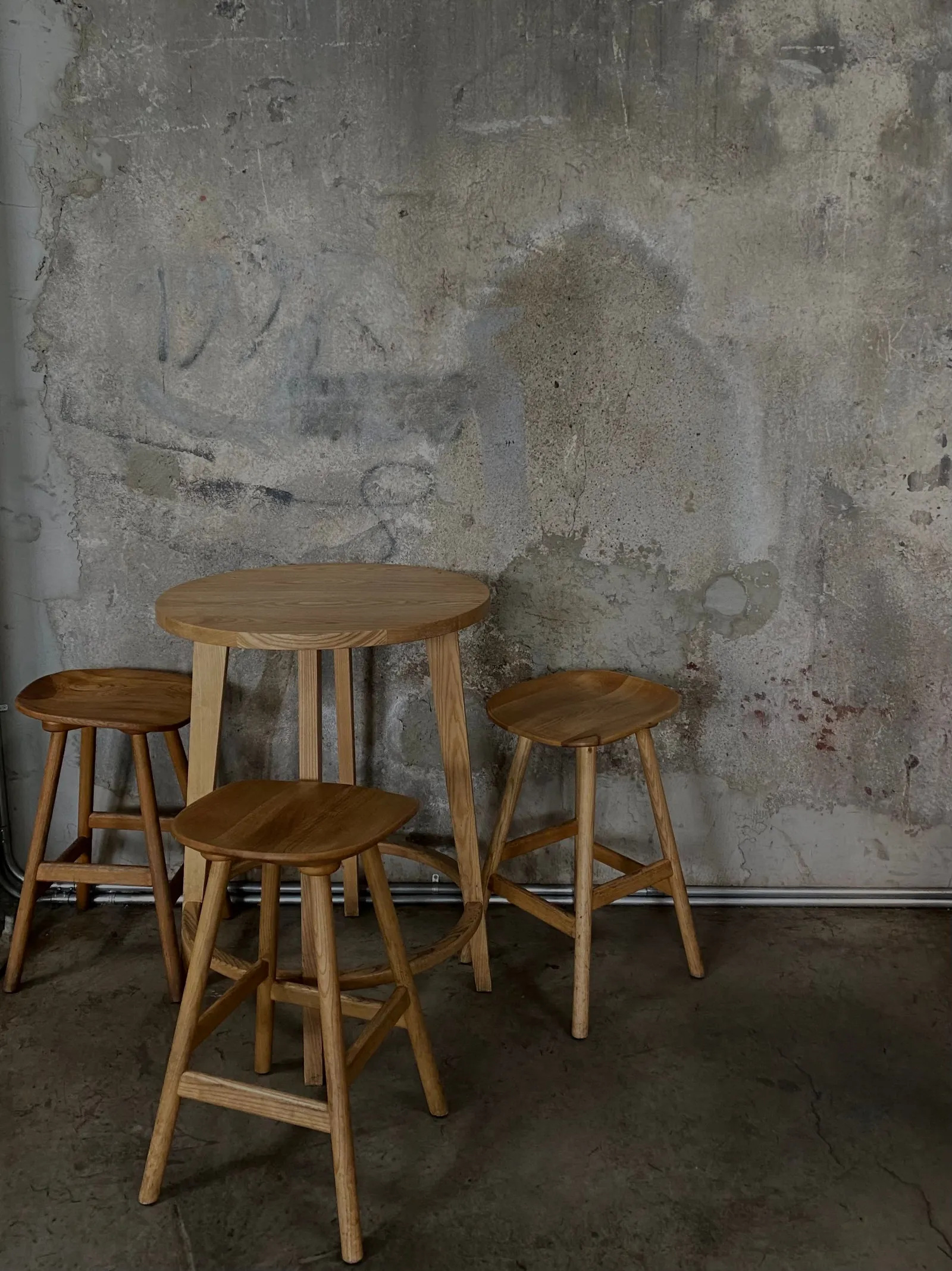 Textured grey wall with a wooden table and stools